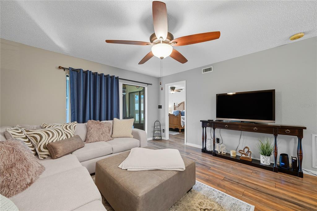 A living room features a sectional sofa, a large ottoman, and a television on a console — 2400 WINDING CREEK BOULEVARD UNIT 9-202, CLEARWATER, FL
