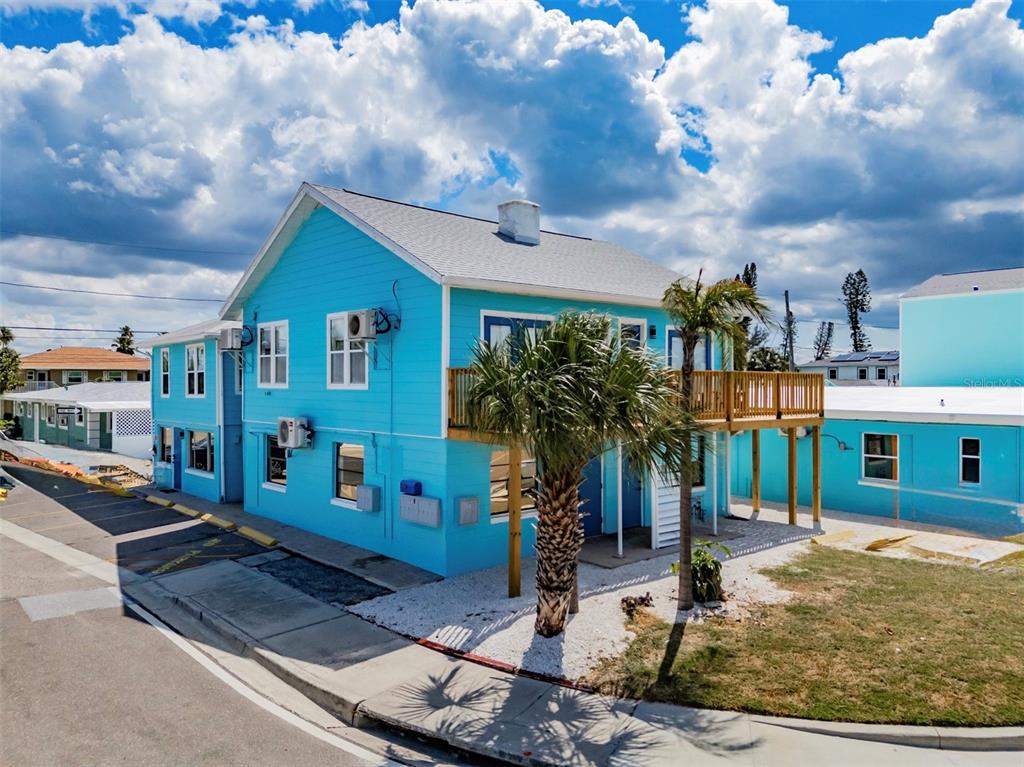 A bright blue two-story house features a wooden deck and a palm tree in front — 13343 GULF BOULEVARD UNIT 14, MADEIRA BEACH, FL