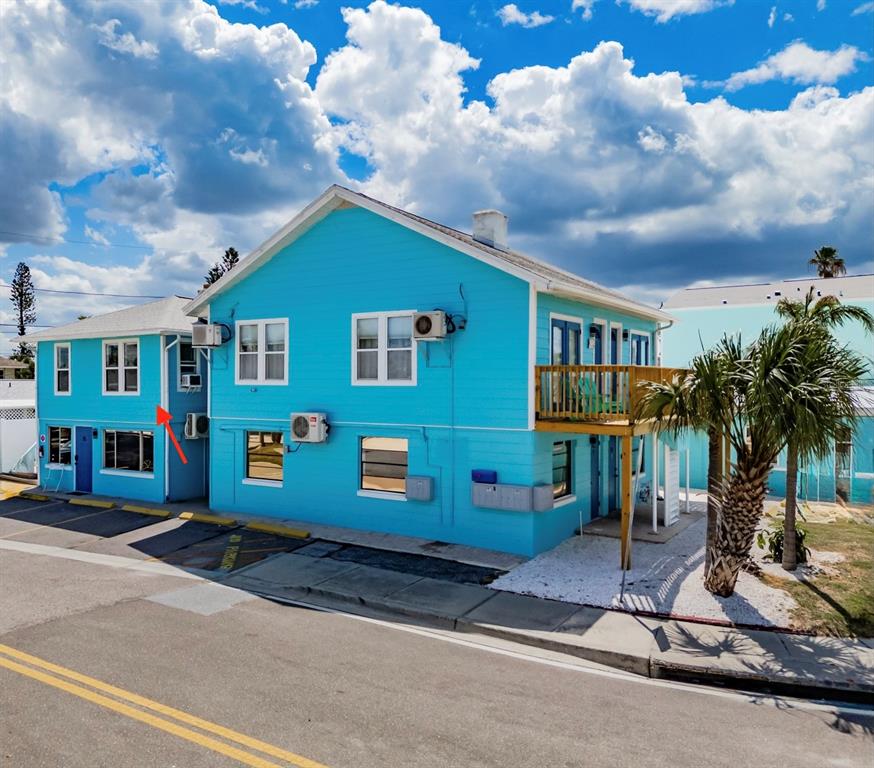 A bright blue two-story building with white trim and a wooden balcony stands outdoors — 13343 GULF BOULEVARD UNIT 14, MADEIRA BEACH, FL