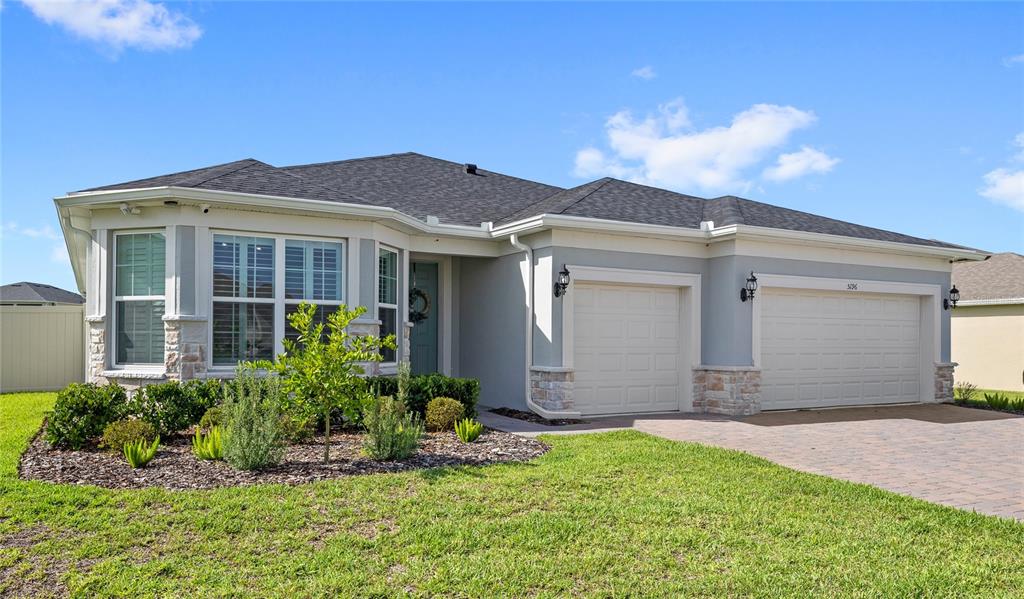 A single-story house with a gray stucco exterior, stone accents, and a three-car garage — 5196 FOOTHILLS PRESERVE LOOP, MOUNT DORA, FL