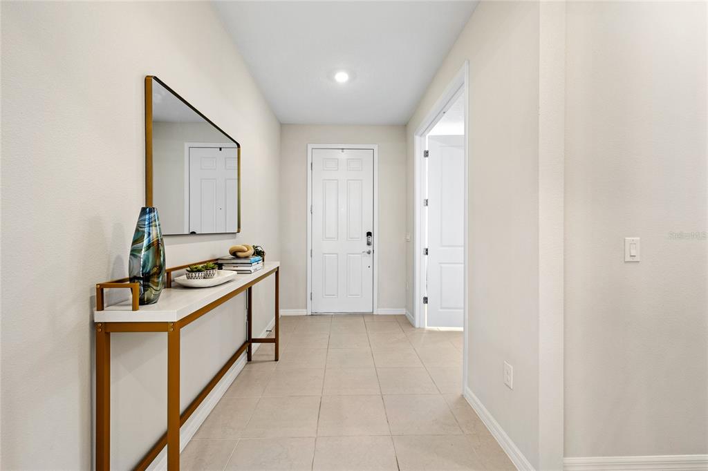 A bright entryway features a console table, a wall mirror, and tile flooring — 5196 FOOTHILLS PRESERVE LOOP, MOUNT DORA, FL