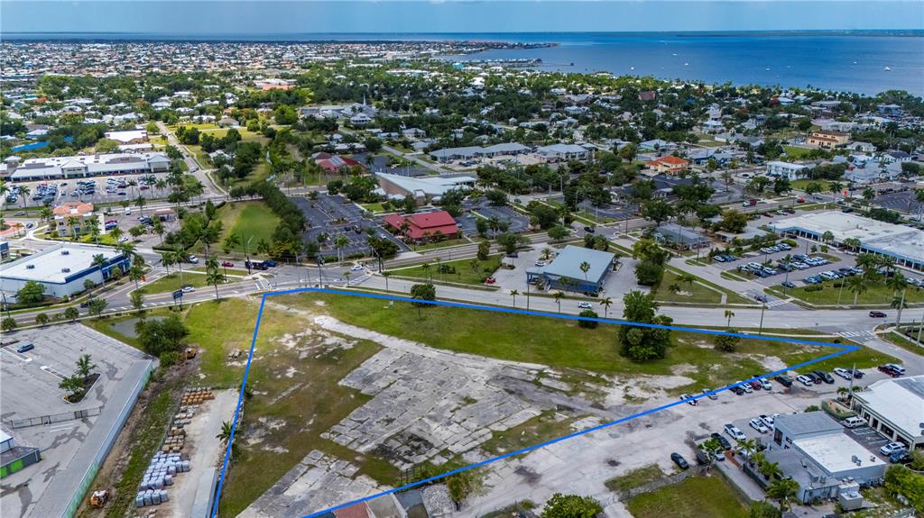 An aerial view shows a vacant, triangular-shaped lot bordered by paved roads and commercial buildings — 500 TAMIAMI TRAIL, PUNTA GORDA, FL