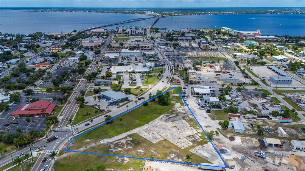 An aerial view shows a triangular vacant lot outlined in blue near a coastal town — 500 TAMIAMI TRAIL, PUNTA GORDA, FL