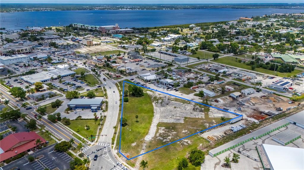 An aerial view shows a triangular vacant lot outlined in blue near a coastal city — 500 TAMIAMI TRAIL, PUNTA GORDA, FL