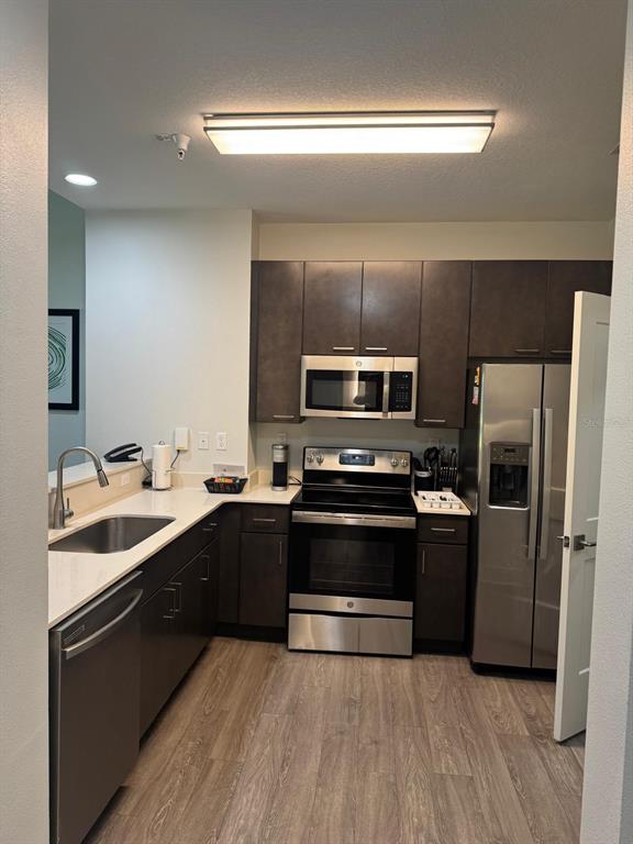 A kitchen features dark wood cabinets, stainless steel appliances, and light countertops — 14501 GROVE RESORT AVENUE UNIT 3135, WINTER GARDEN, FL