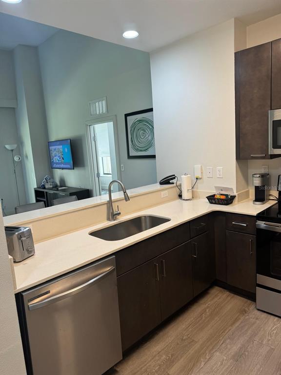 A kitchen features dark wood cabinets, stainless steel appliances, and a light-colored countertop — 14501 GROVE RESORT AVENUE UNIT 3135, WINTER GARDEN, FL