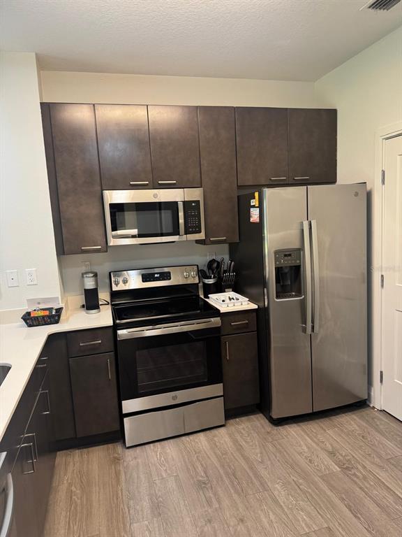 A kitchen features dark wood cabinets, stainless steel appliances, and light-colored countertops — 14501 GROVE RESORT AVENUE UNIT 3135, WINTER GARDEN, FL