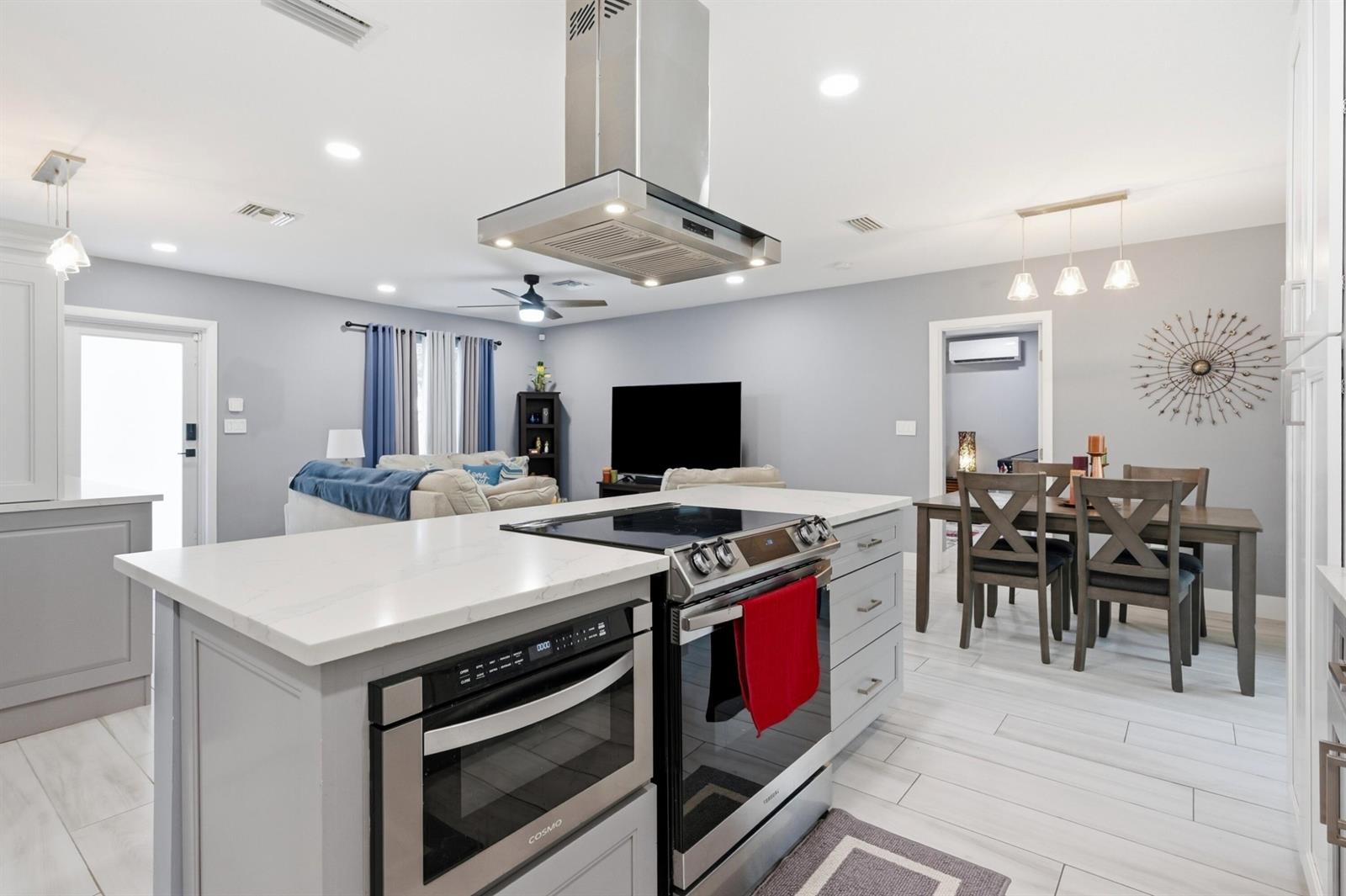 A modern kitchen features white upper cabinets, gray lower cabinets, stainless steel appliances, and quartz countertops — 141 SE 8th Street, Pompano Beach FL 33060, POMPANO BEACH, FL