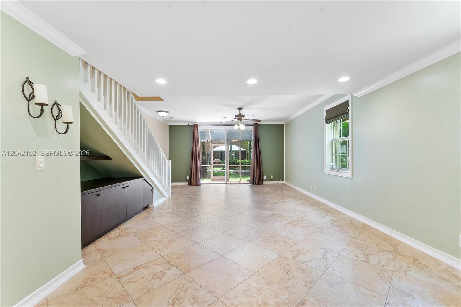 A living room features light green walls, tile flooring, a staircase, and sliding glass doors — 1552 Barcelona Way # 19, Weston FL 33327, WESTON, FL