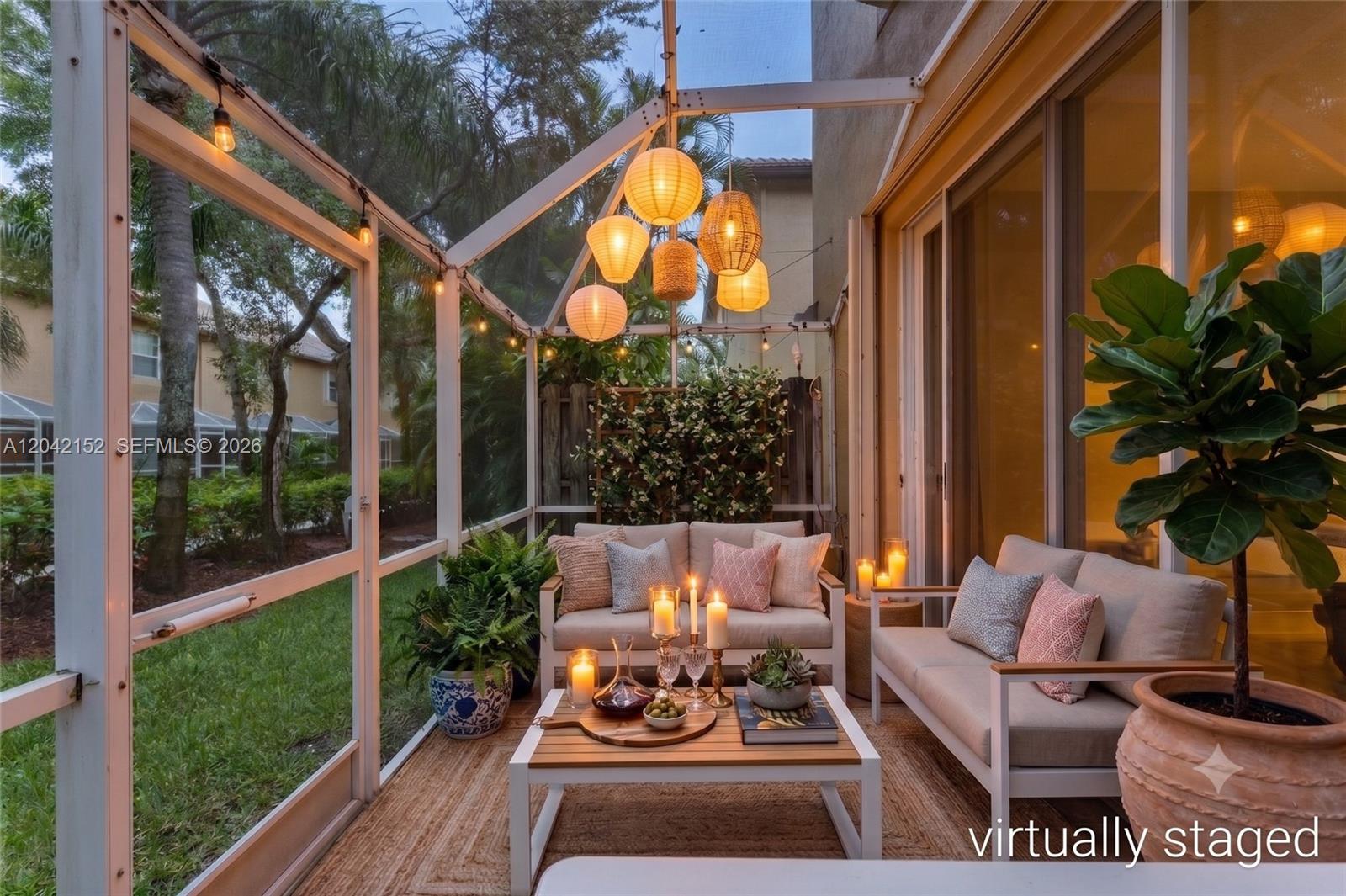 A screened-in patio features two sofas, a coffee table, and hanging paper lanterns — 1552 Barcelona Way # 19, Weston FL 33327, WESTON, FL