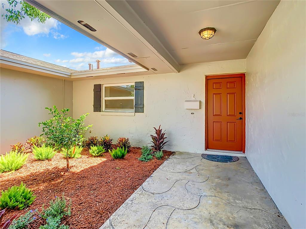 An exterior view of a home entrance with a red door and a landscaped courtyard — 2642 BROOKSIDE COURT, MAITLAND, FL