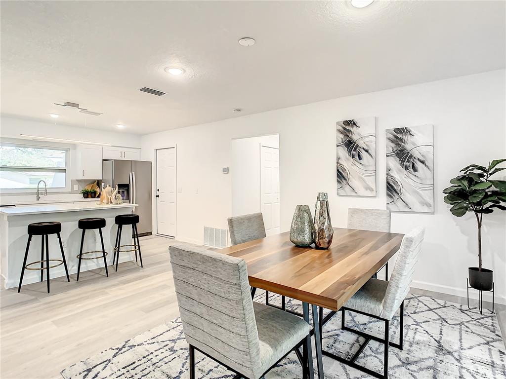 A dining area with a wooden table and chairs sits adjacent to a modern kitchen — 2642 BROOKSIDE COURT, MAITLAND, FL