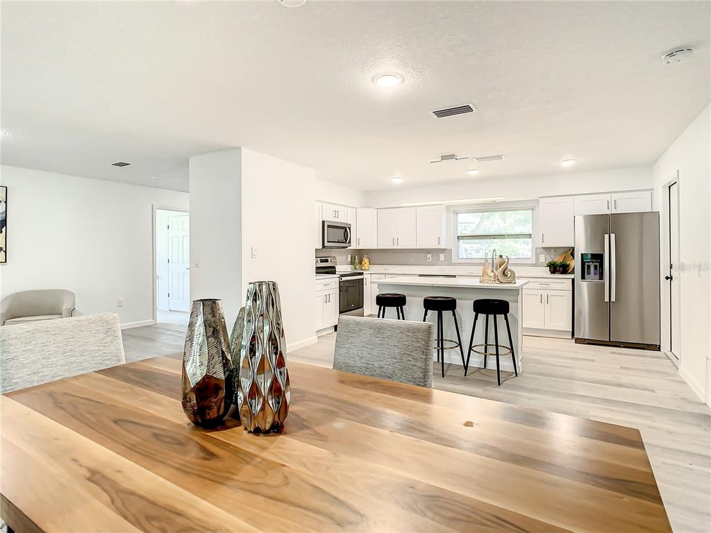 A dining area with a wood table overlooks a modern kitchen with white cabinetry — 2642 BROOKSIDE COURT, MAITLAND, FL