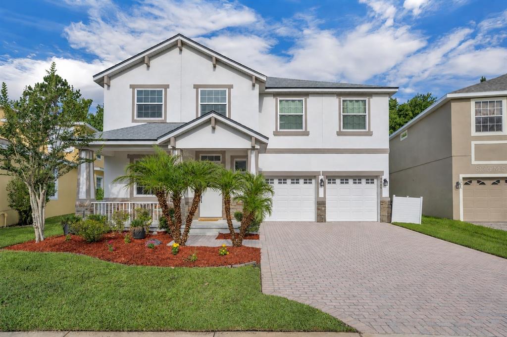 A two-story house with a white exterior, a paved driveway, and a front garden — 9906 MOSS ROSE WAY, ORLANDO, FL