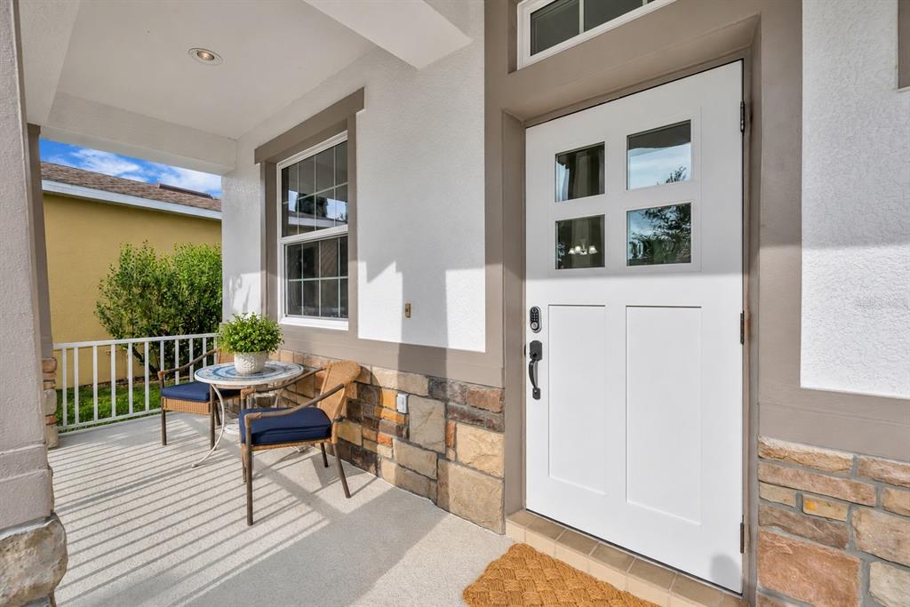 A white front door with four glass panes sits next to a small patio area — 9906 MOSS ROSE WAY, ORLANDO, FL