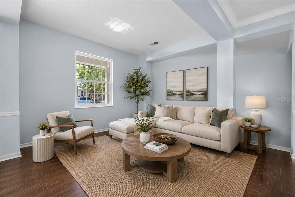 A living room features a beige sectional, a round wooden coffee table, and light blue walls — 9906 MOSS ROSE WAY, ORLANDO, FL