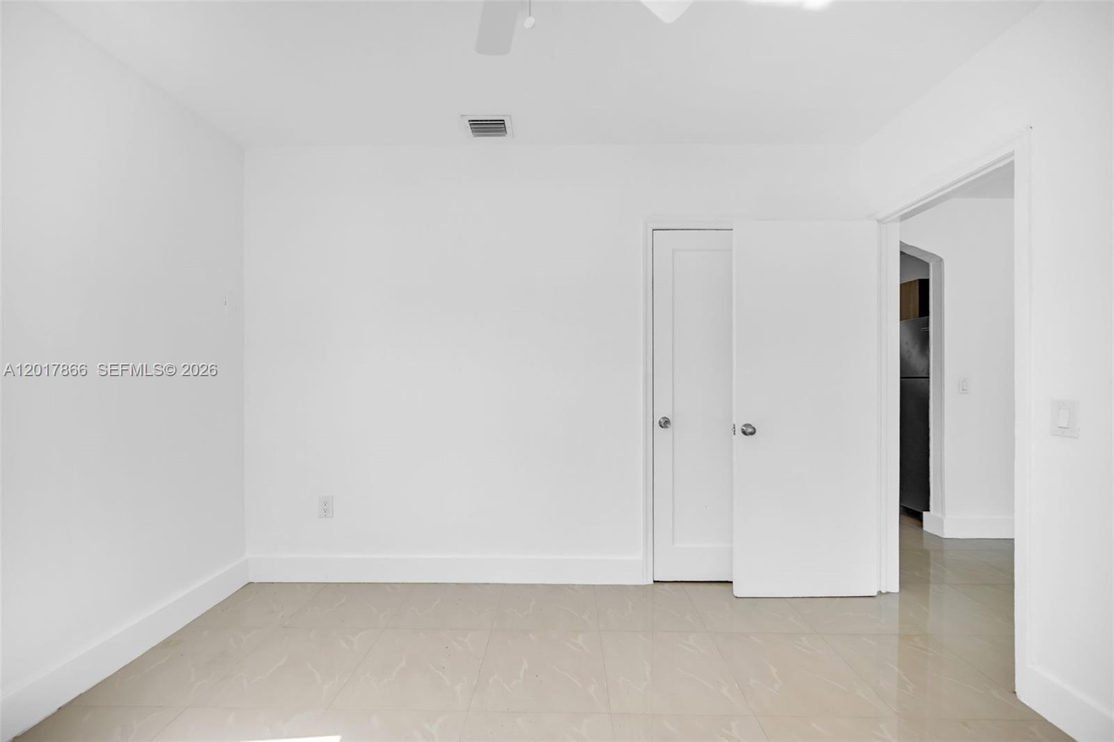 A sparsely furnished room features white walls, tile flooring, and a single interior door — 555 NW 90th St, El Portal FL 33150, EL PORTAL, FL