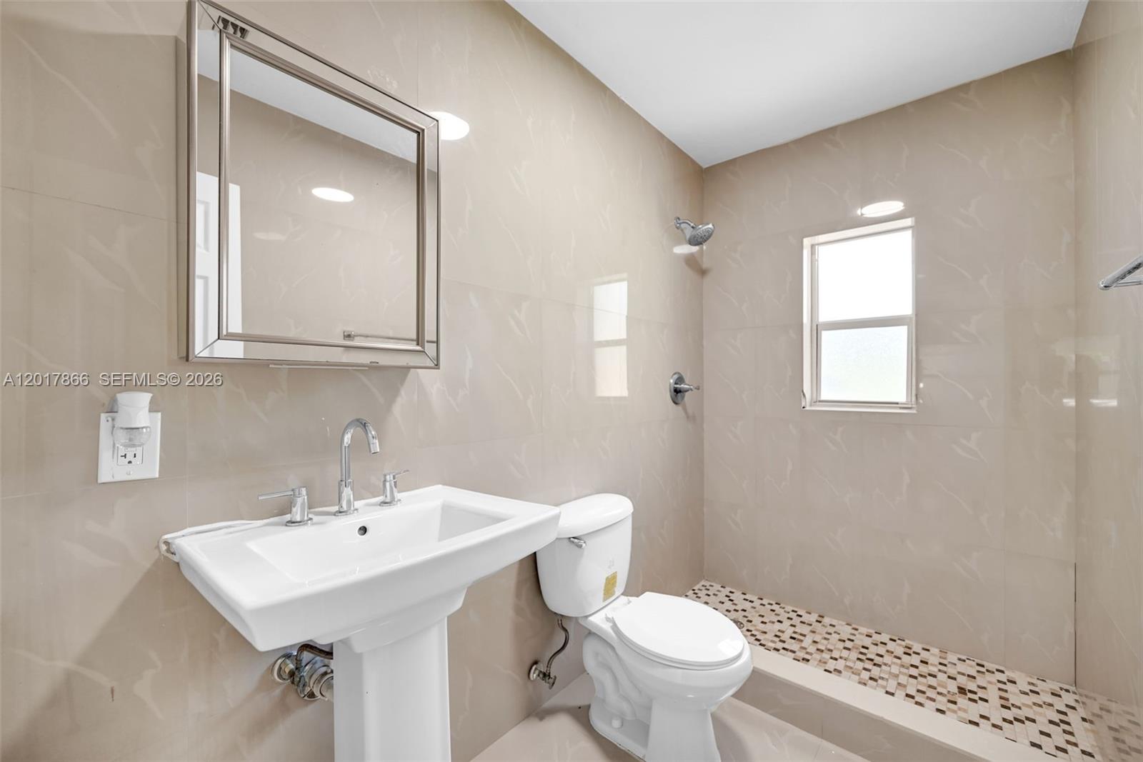 A bathroom features a pedestal sink, a toilet, and a tiled walk-in shower — 555 NW 90th St, El Portal FL 33150, EL PORTAL, FL