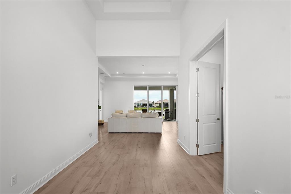 A bright hallway leads into a living room with light wood floors and large windows — 8472 SW CANTANTE WAY, PORT ST LUCIE, FL