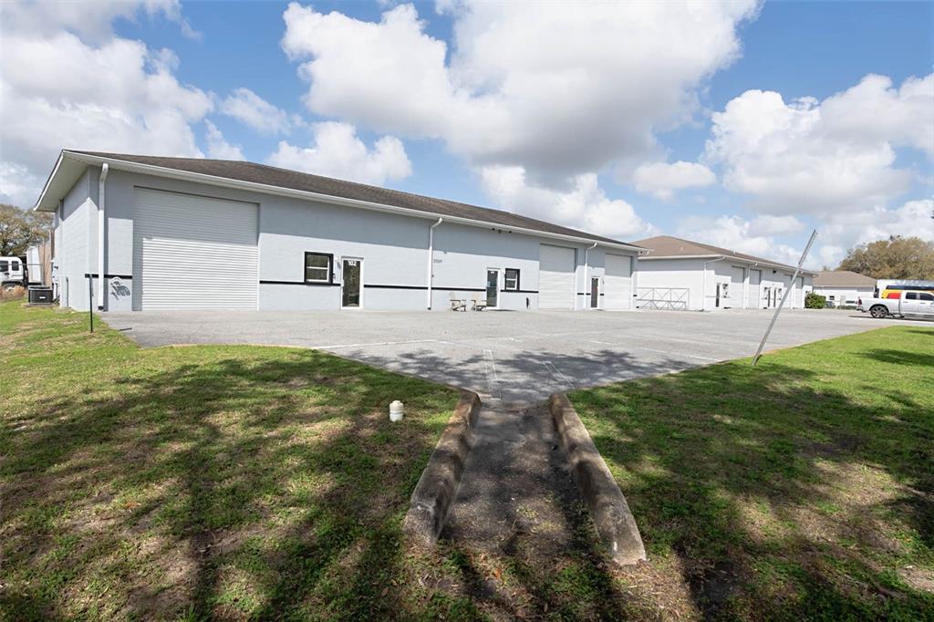 A gray industrial warehouse building features multiple roll-up doors and a paved parking lot — 3398 SW 74TH AVENUE, OCALA, FL