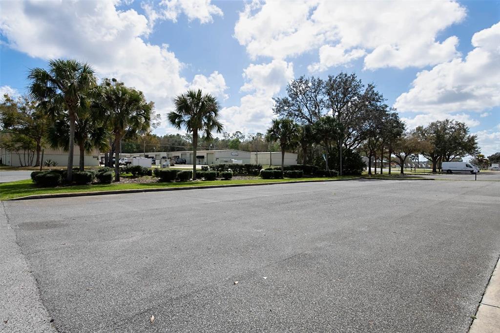 A large, empty asphalt parking lot sits in front of palm trees and storage buildings — 3398 SW 74TH AVENUE, OCALA, FL