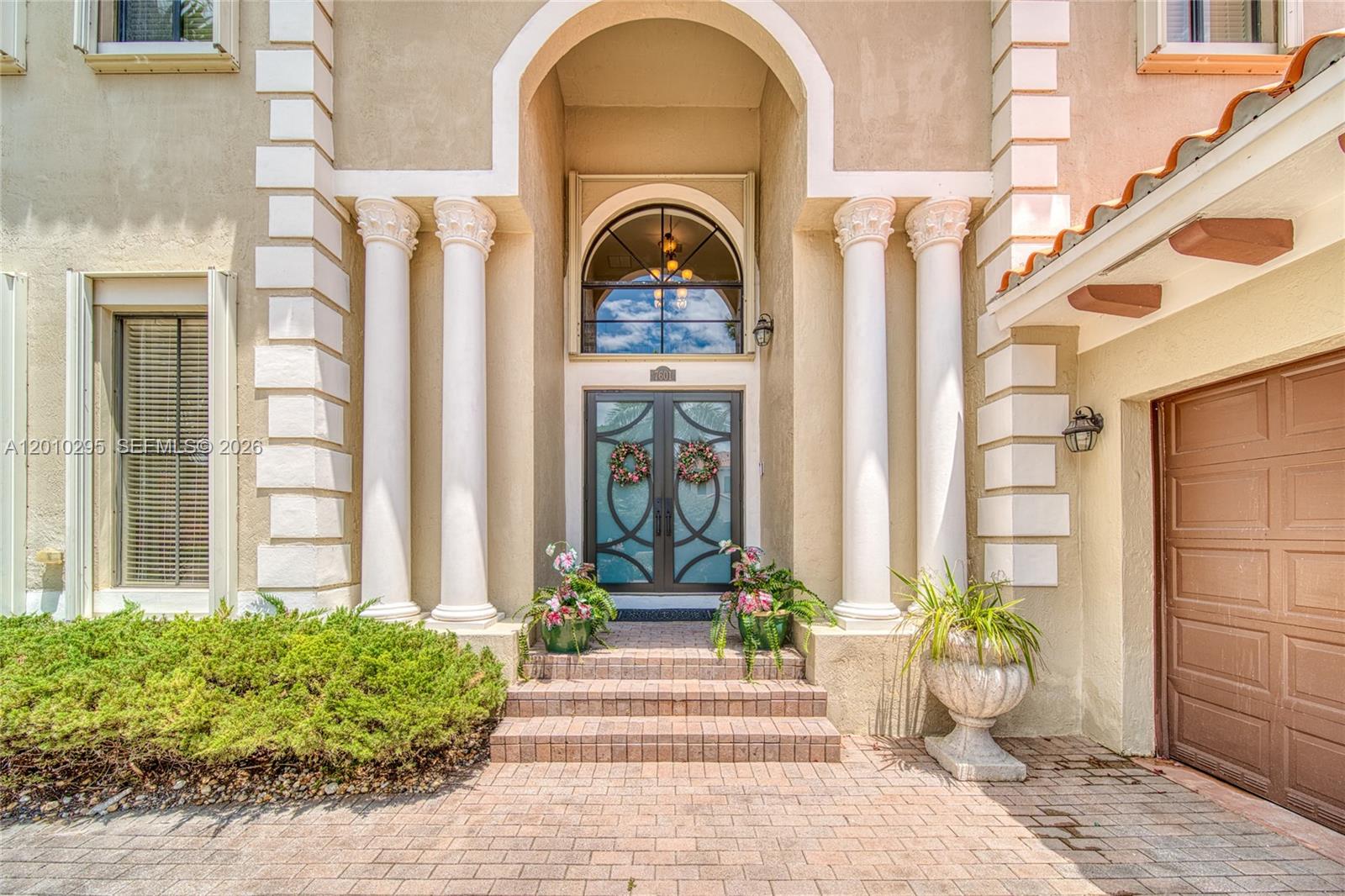 The exterior of a house features a double door entrance framed by four white columns — 7601 SW 187th St, Cutler Bay FL 33157, CUTLER BAY, FL