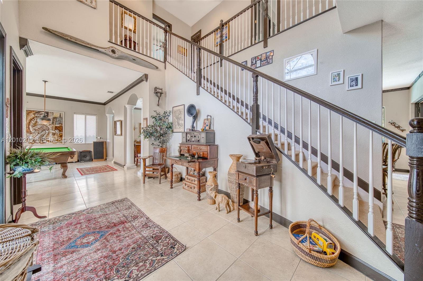 A spacious foyer features a grand staircase, tile flooring, and an adjacent room with billiards — 7601 SW 187th St, Cutler Bay FL 33157, CUTLER BAY, FL