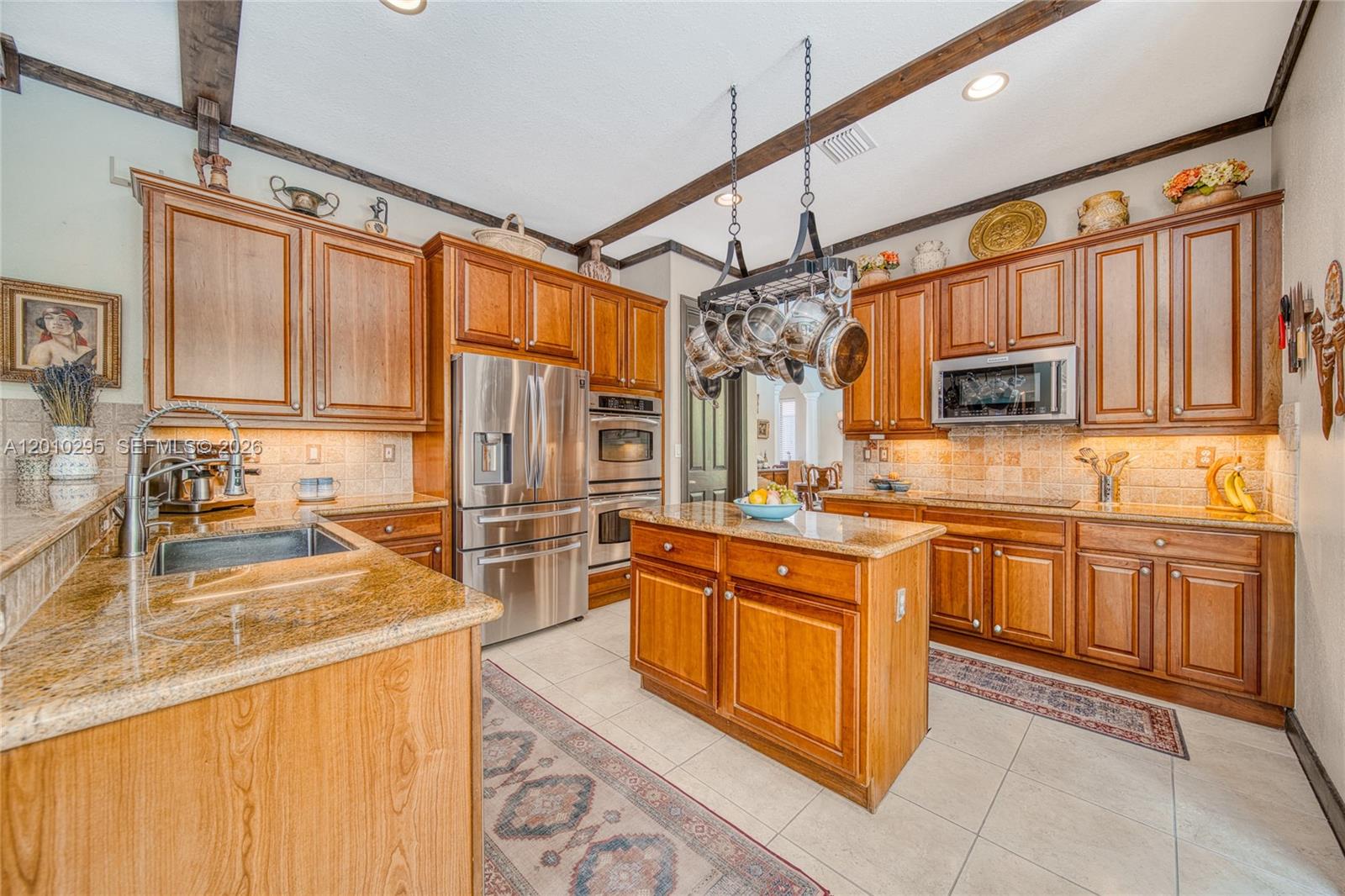 A kitchen features wood cabinets, granite countertops, stainless steel appliances, and a hanging pot rack — 7601 SW 187th St, Cutler Bay FL 33157, CUTLER BAY, FL