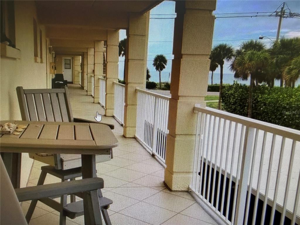 A balcony with a table and chairs overlooks palm trees and the ocean — 3802 GULF OF MEXICO DRIVE UNIT A204, LONGBOAT KEY, FL