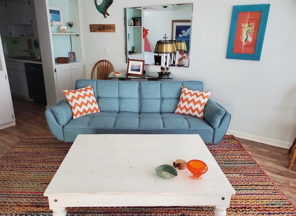 A living room features a blue tufted sofa, a white coffee table, and a colorful rug — 3802 GULF OF MEXICO DRIVE UNIT A204, LONGBOAT KEY, FL