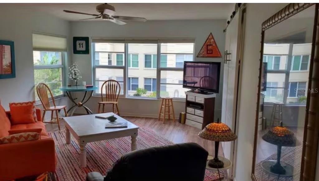 A living room features an orange sofa, a coffee table, and large windows with blinds — 3802 GULF OF MEXICO DRIVE UNIT A204, LONGBOAT KEY, FL