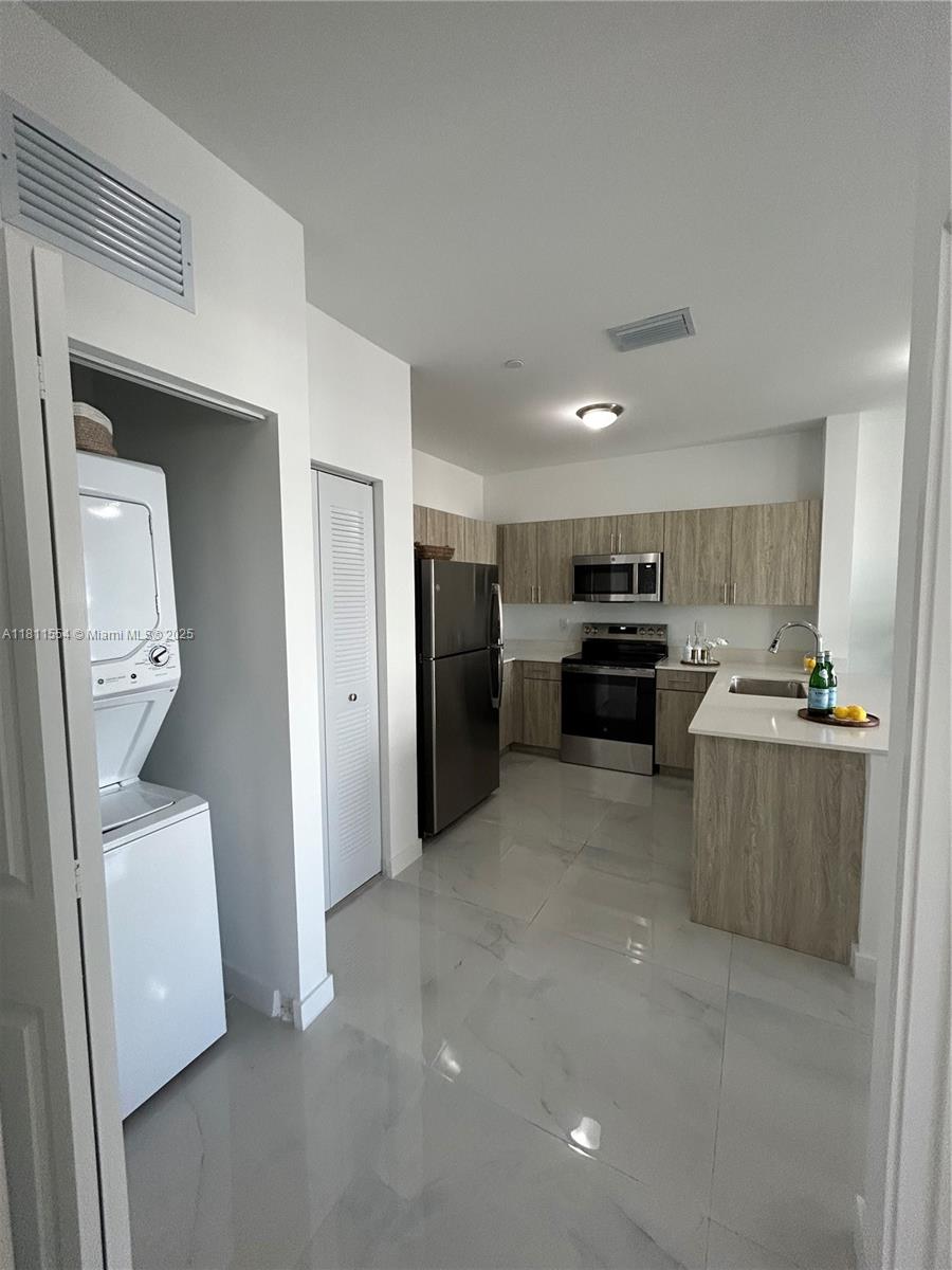 A kitchen features stainless steel appliances, light wood cabinets, and a white tiled floor — 1010 SW 69th Ave # 212, Miami FL 33144, MIAMI, FL