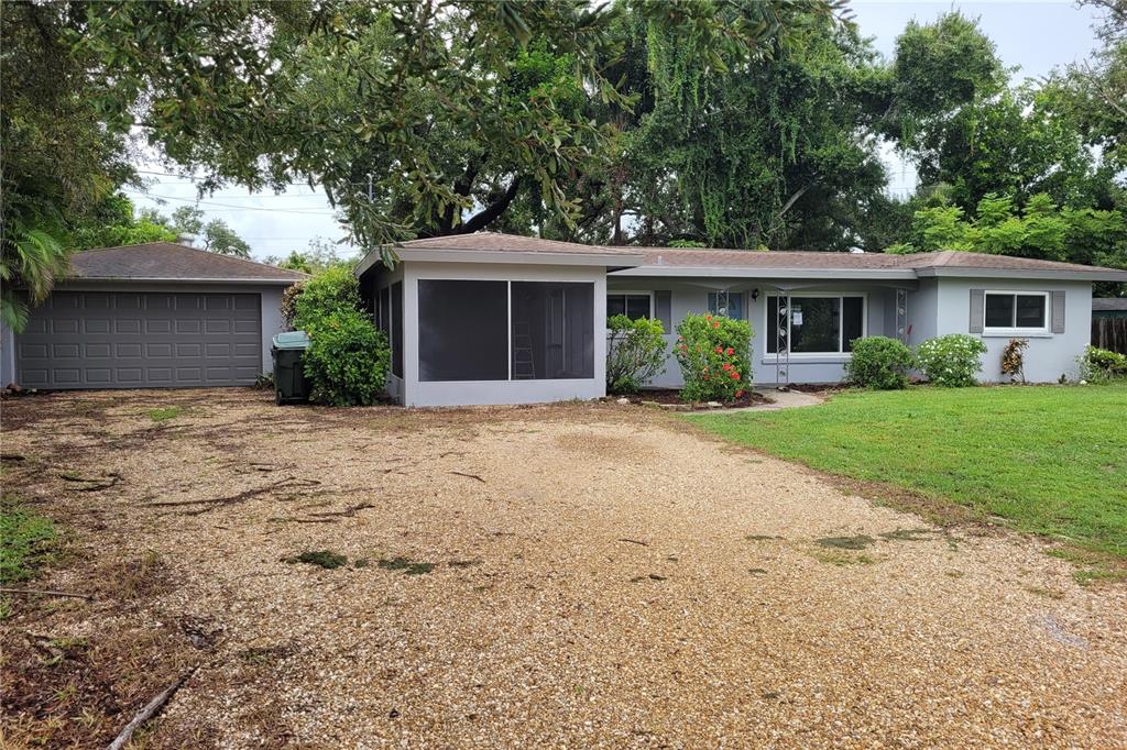 A single-story house with a light gray exterior, a screened-in porch, and a large lawn — 2928 BETTY DRIVE, SARASOTA, FL