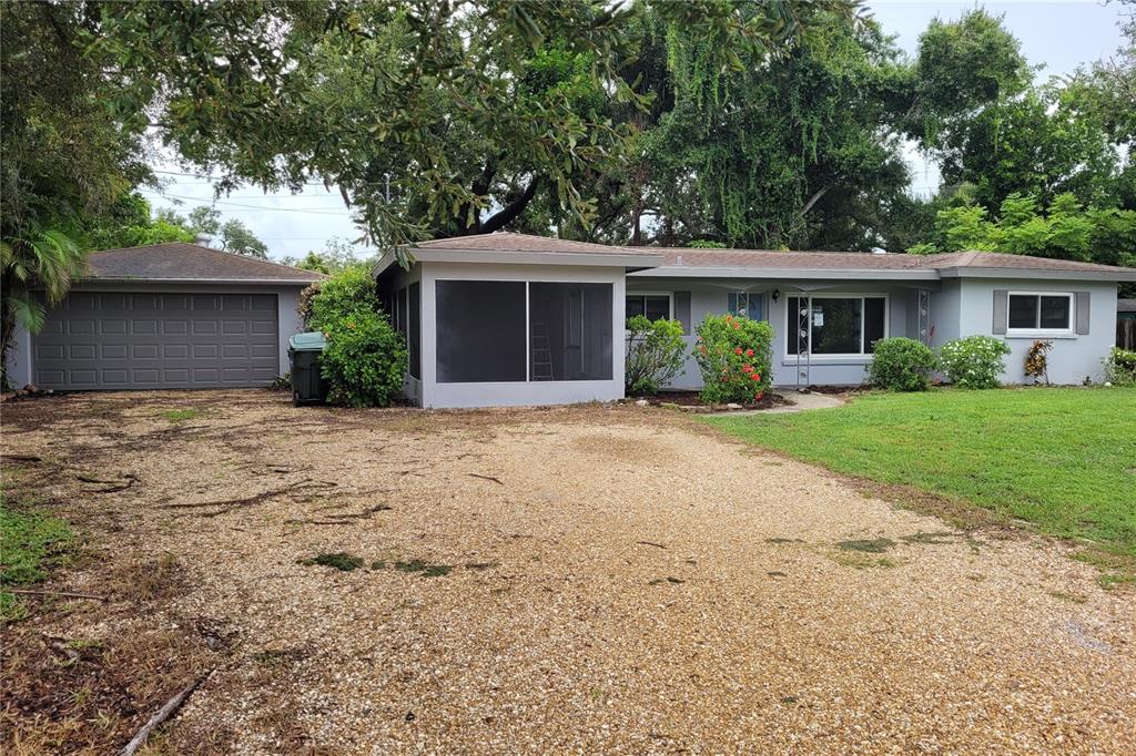 A single-story house with a gravel driveway, a screened-in porch, and a detached garage — 2928 BETTY DRIVE, SARASOTA, FL