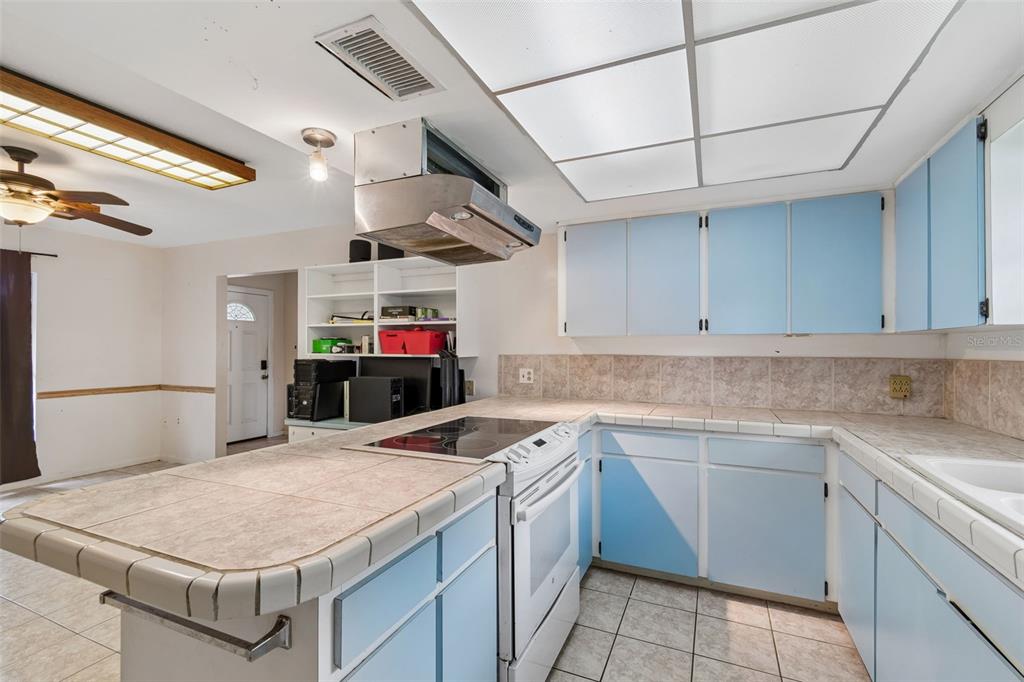 A kitchen features light blue cabinets, tiled countertops, a drop-in range, and a drop ceiling — 418 DEWOLF ROAD, BRANDON, FL