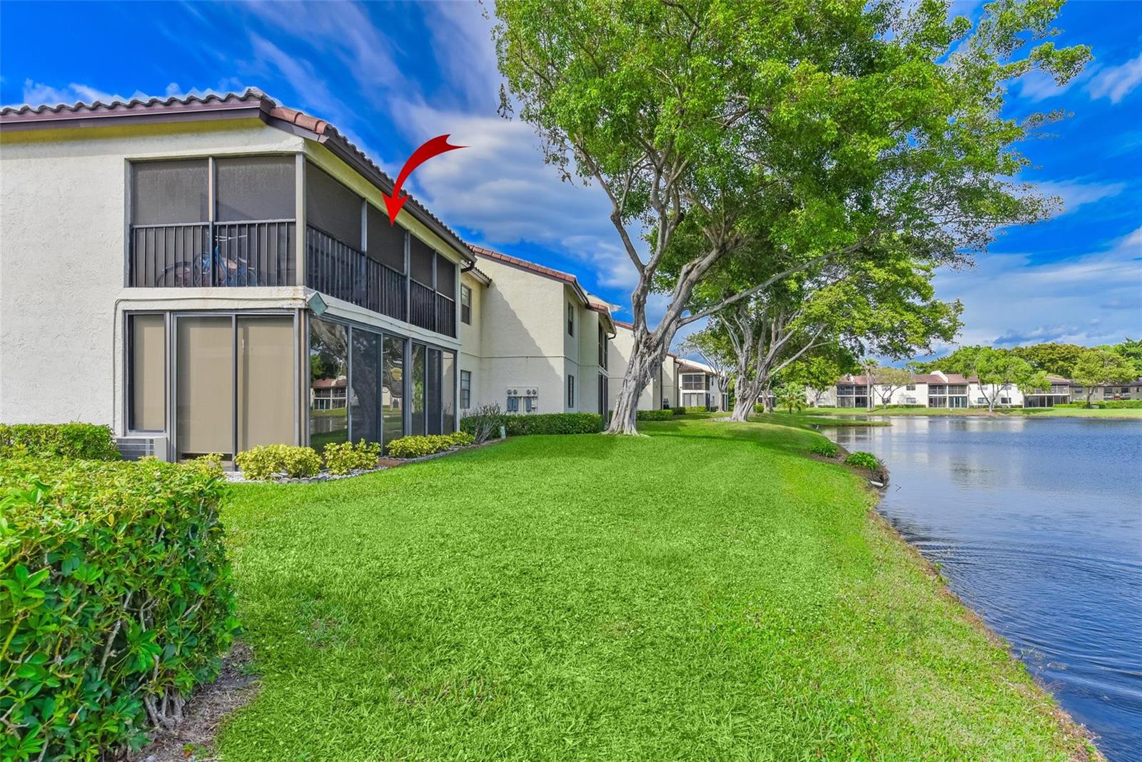 A two-story apartment building with screened balconies overlooks a grassy lawn and a lake — 21827 Arriba Real # L, Boca Raton FL 33433, BOCA RATON, FL