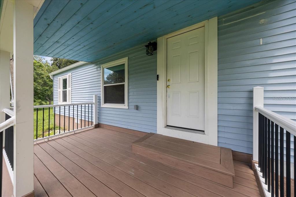 A light blue house exterior features a wooden porch deck, white railings, and a white door — 10717 SE 129TH STREET, BELLEVIEW, FL