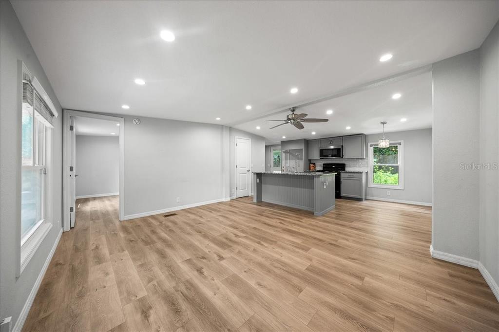 An open-concept living area features light wood flooring, gray walls, and a kitchen island — 10717 SE 129TH STREET, BELLEVIEW, FL