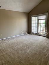A carpeted living room with a vaulted ceiling and a glass door leading to a balcony — 236 AFTON SQUARE UNIT 306, ALTAMONTE SPRINGS, FL