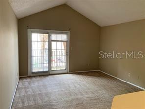 An empty room with beige carpet, tan walls, a vaulted ceiling, and sliding glass doors — 236 AFTON SQUARE UNIT 306, ALTAMONTE SPRINGS, FL