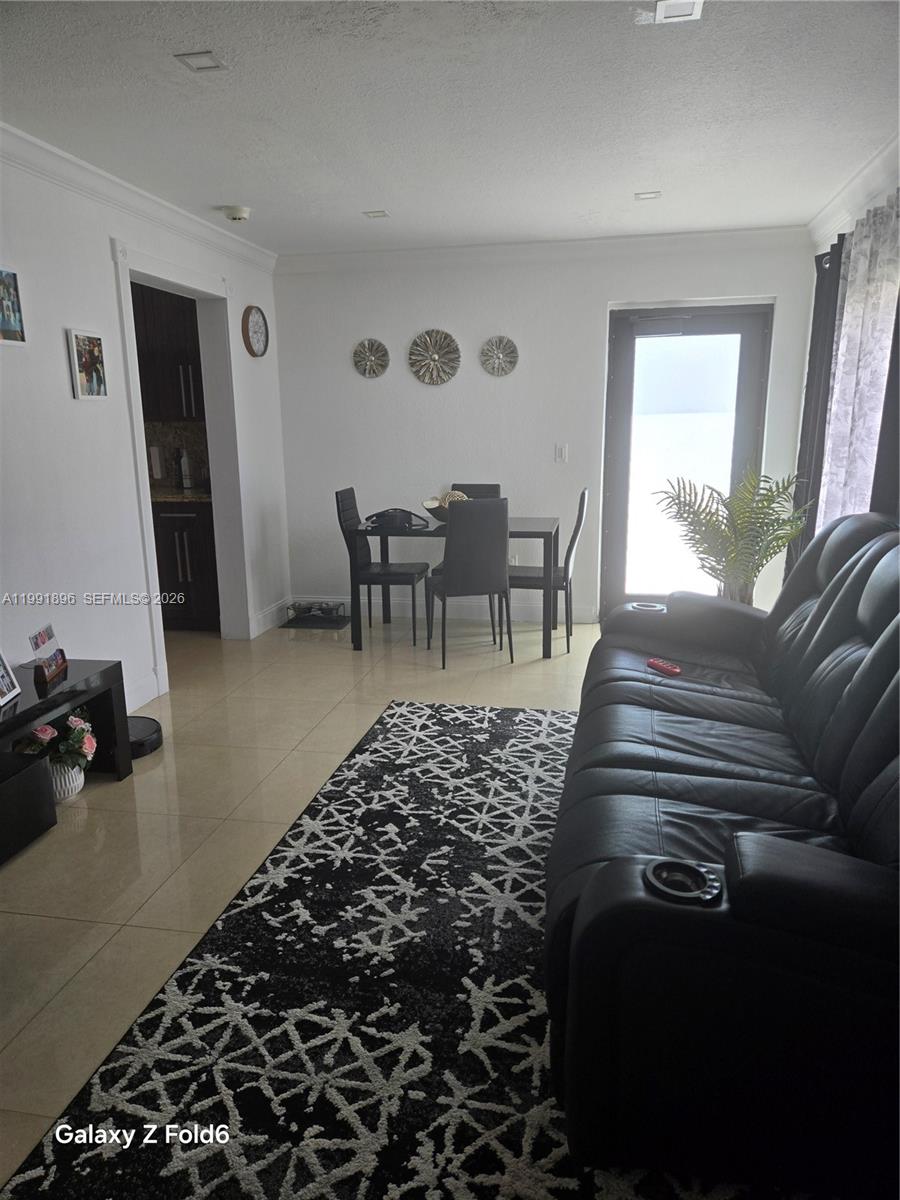 A living and dining area features tile floors, a black leather sofa, and a rug — 234 E 44th St, Hialeah FL 33013, HIALEAH, FL