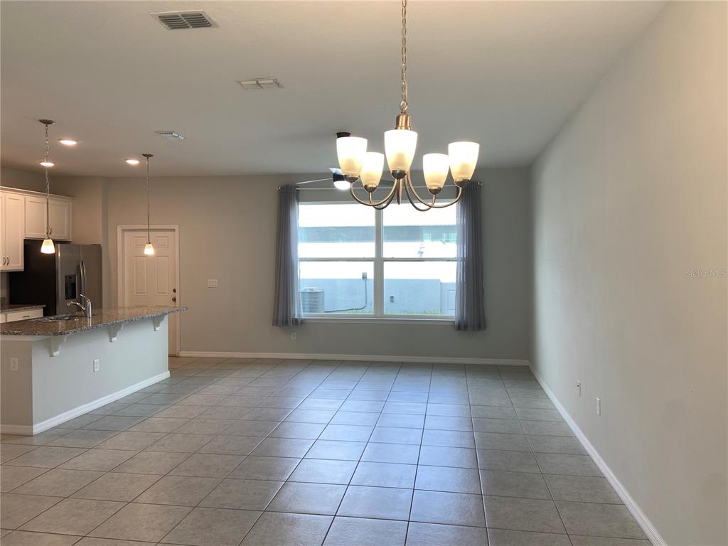 An open-concept dining area features tile flooring, a chandelier, and an adjacent kitchen island — 5029 AVALON PARK BOULEVARD, WESLEY CHAPEL, FL