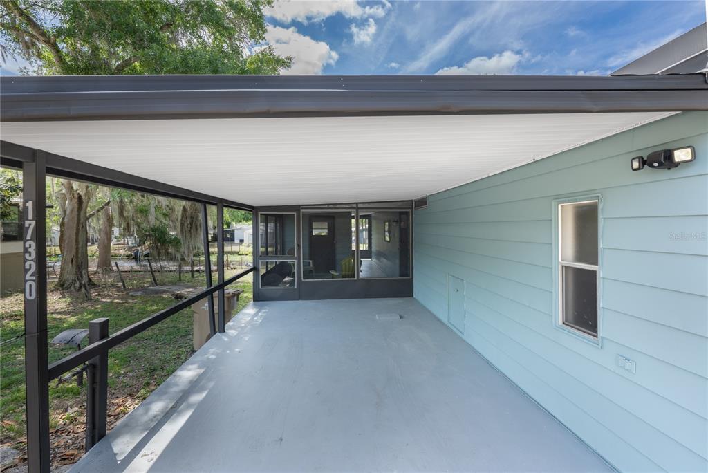 A covered patio with a light blue exterior wall, concrete floor, and screened-in enclosure — 17320 PALM DRIVE, MONTVERDE, FL