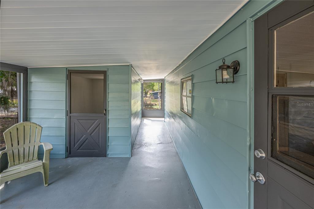 A covered porch features blue horizontal siding, a gray floor, and two dark-framed doors — 17320 PALM DRIVE, MONTVERDE, FL