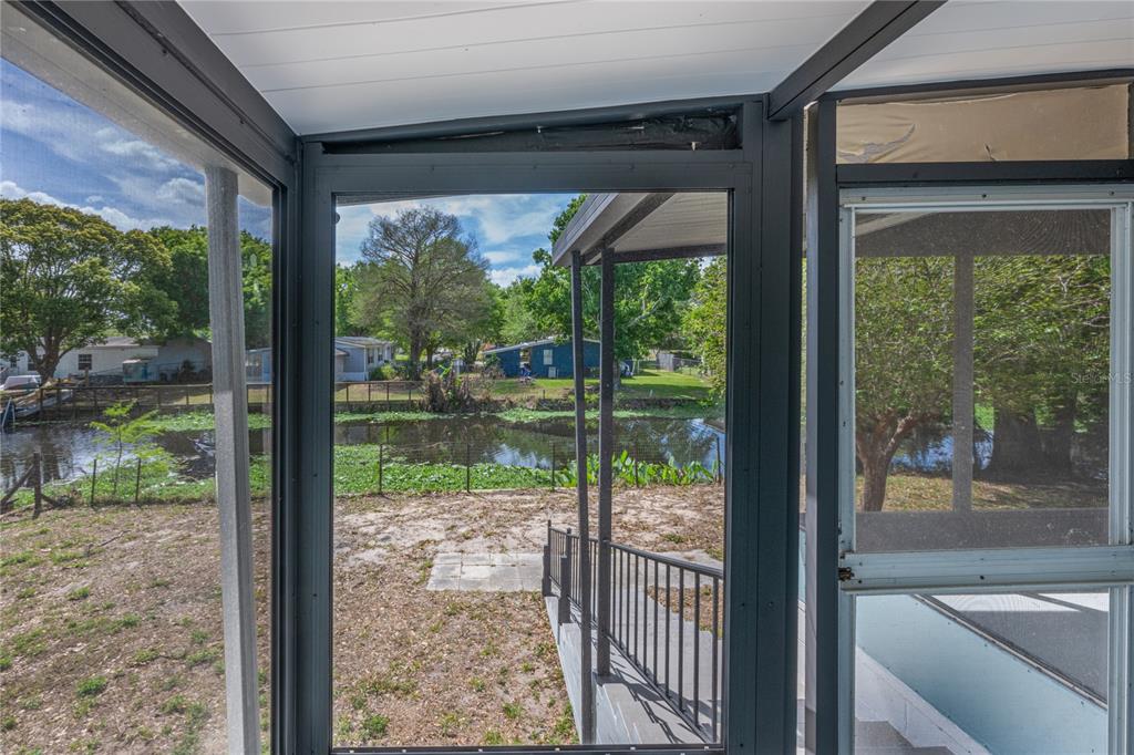 A view of a canal and backyard from inside a screened-in porch — 17320 PALM DRIVE, MONTVERDE, FL