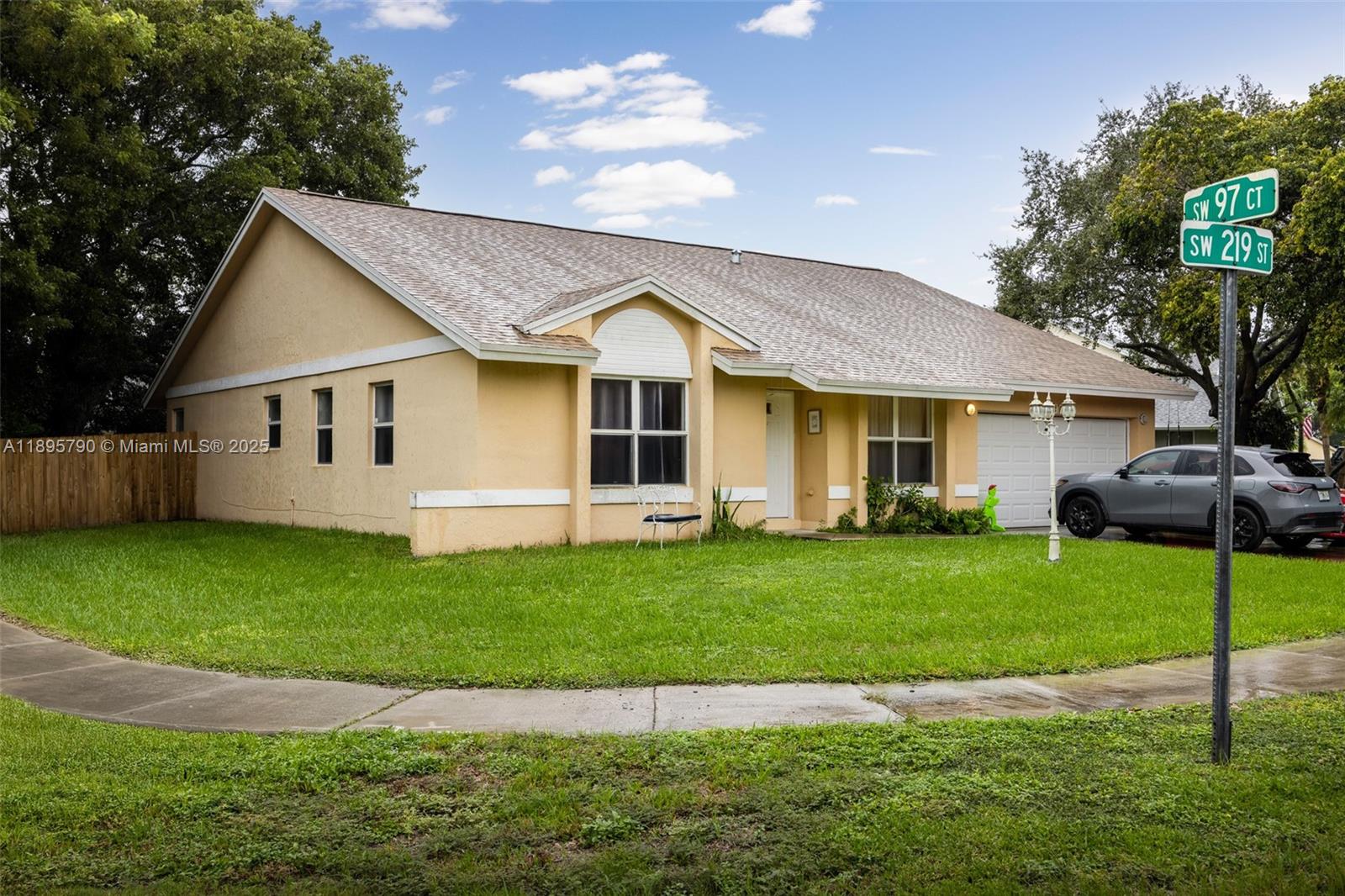 A single-story, light-yellow house with a two-car garage sits on a corner lot — 9730 SW 219th St, Cutler Bay FL 33190, CUTLER BAY, FL