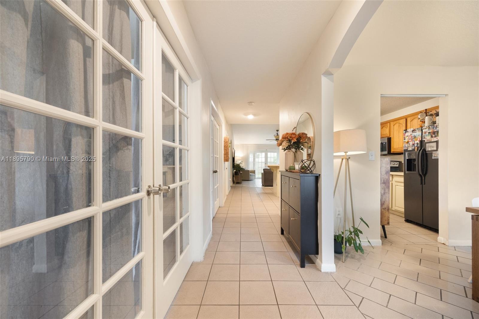 A tiled hallway leads past a black cabinet and floor lamp toward a kitchen — 9730 SW 219th St, Cutler Bay FL 33190, CUTLER BAY, FL