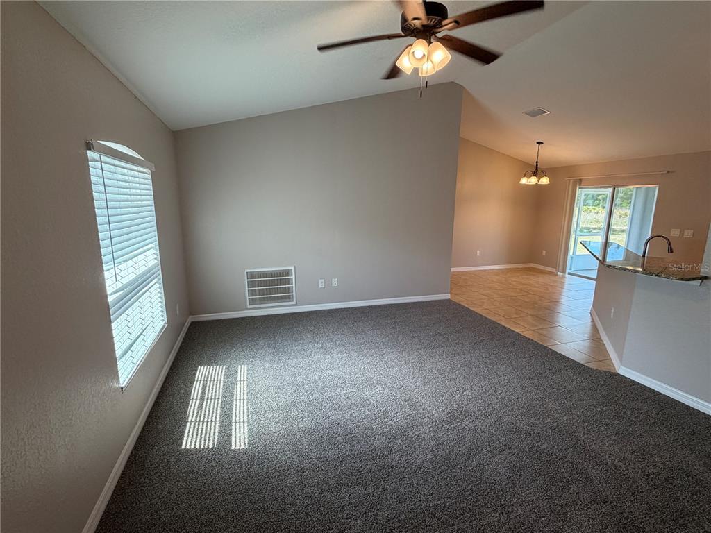 A carpeted living room with a ceiling fan flows into a tiled dining area — 15369 SW 65TH TERRACE ROAD, OCALA, FL