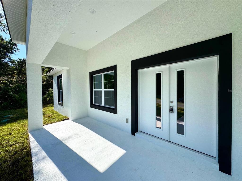 A covered entryway features white walls, black trim, a double front door, and a window — 10160 N ACADEMY DRIVE, CITRUS SPRINGS, FL