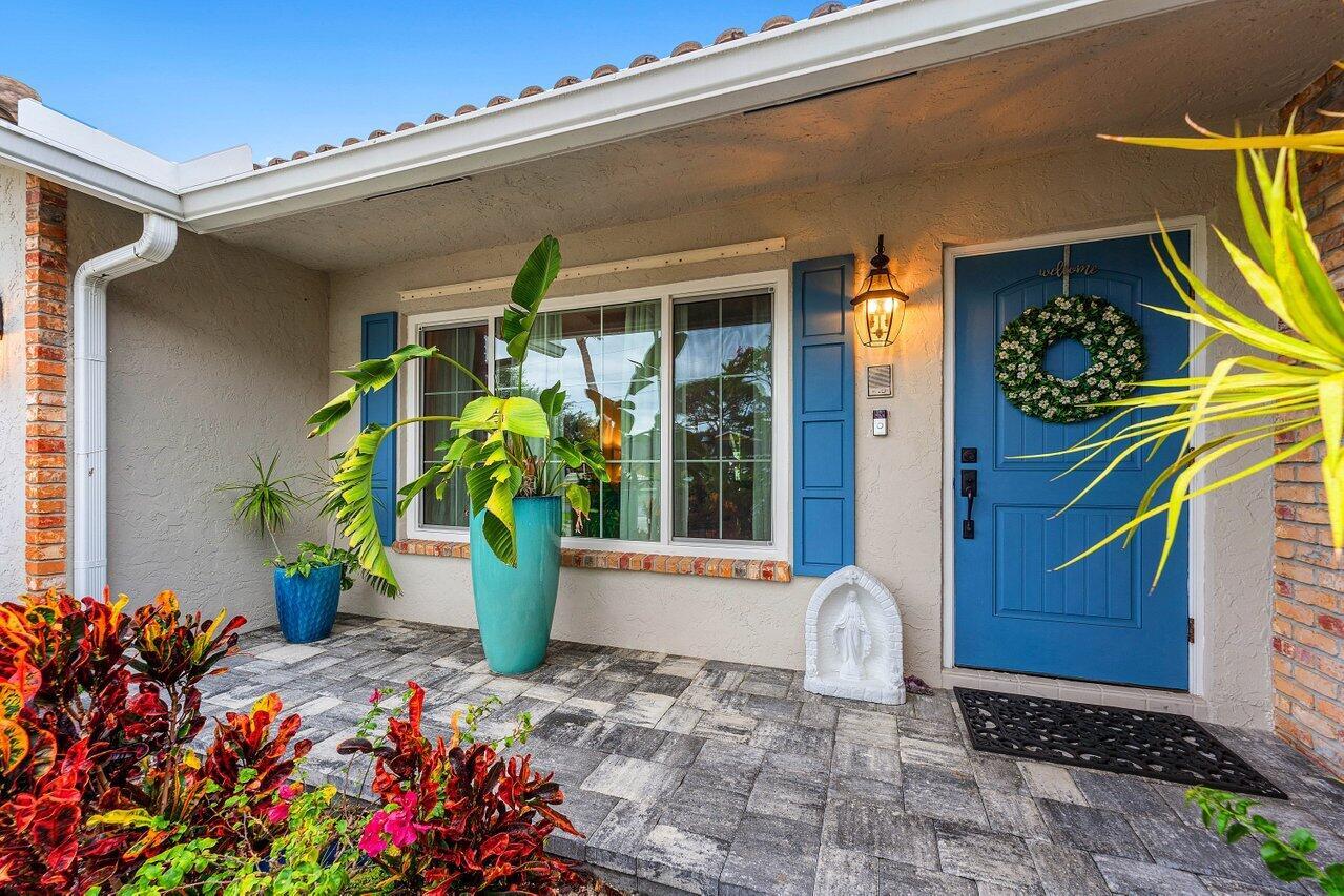 A front porch with a blue door, a large potted plant, and stone paver flooring — 2527 SW 12th Street, Boynton Beach FL 33426, BOYNTON BEACH, FL